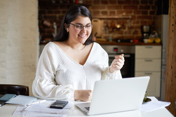 Energetic young female interpreter with chubby cheeks using laptop participating in video...