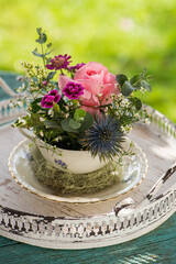 Obraz na płótnie Canvas Old coffee cup with flower arrangement on a table