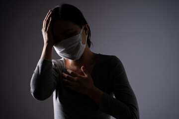Asian woman wearing protective face mask was sick with body pain touching her body and standing isolated on background.