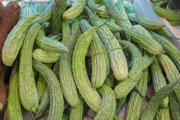 A pile of fresh Bitter Melon fruits (Momordica charantia), widely used in the cuisines of East Asia, South Asia, and Southeast Asia, presented for sale at a market stand.