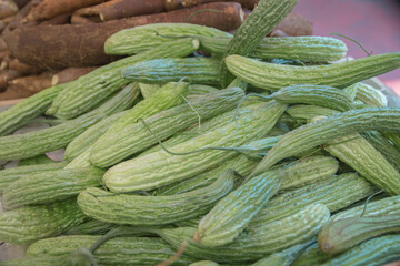 A pile of fresh Bitter Melon fruits (Momordica charantia), widely used in the cuisines of East Asia, South Asia, and Southeast Asia, presented for sale at a market stand.