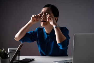 Asian woman in blue shirt sad and crying, working on a laptop at office. isolated on background.
