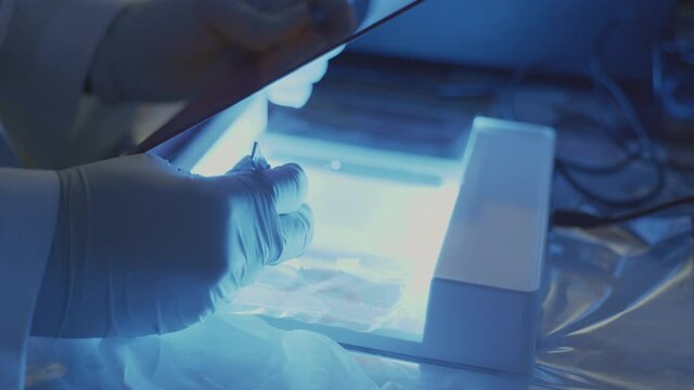 Scientist is cutting the DNA of people infected with the corona virus in the gel under uv box in the laboratory