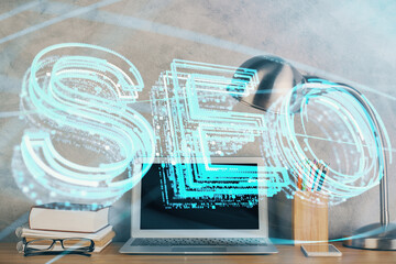 Double exposure of table with computer and seo drawing hologram. Search optimization concept.