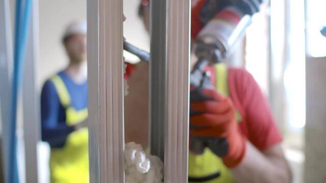Worker using polyurethane foam for gluing drywall frame