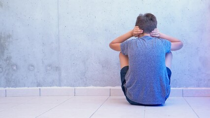 Boy sitting on the floor closing his ears with hands. Autism awareness concept