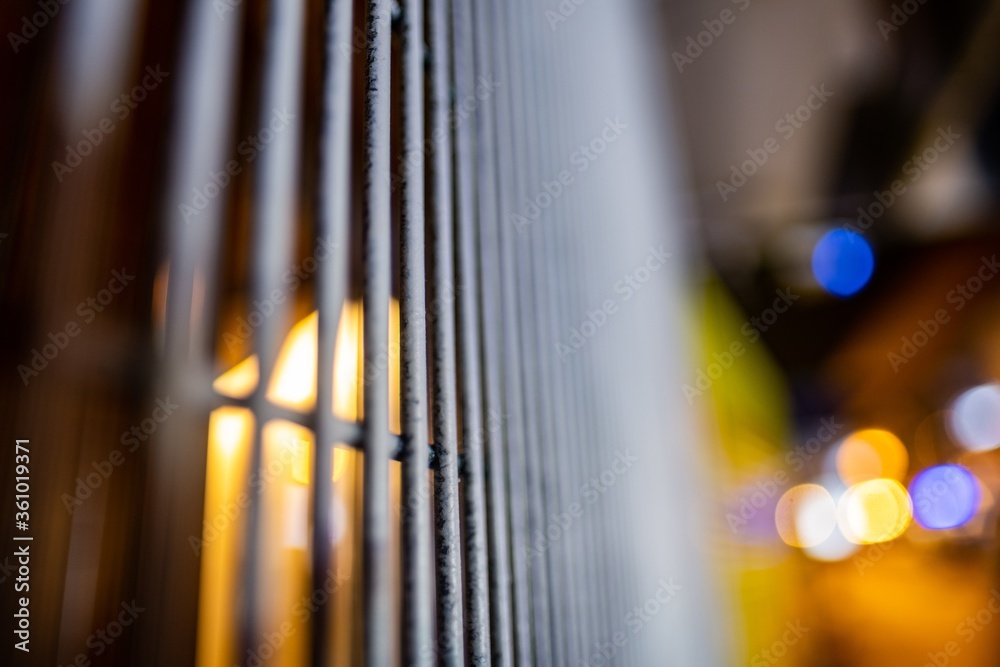 Poster Selective focus shot of grey cage bars and the street lights seen among them