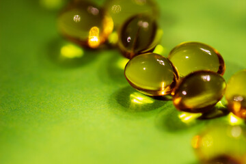 vitamins in capsules are yellow on a green background.close up.the concept of vitamin and mineral deficiency for the health of the body.space for text.