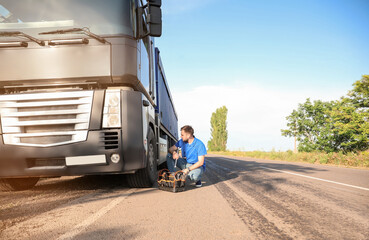 Male driver repairing big truck outdoors