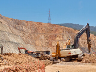 Excavator and hydrohammer during quarrying on the rocky soils. Heavy machinery at earthmoving,...