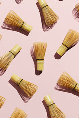 Flatlay of bamboo matcha tea whisks on pink pastel background