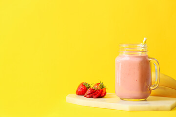 Mason jar of tasty strawberry smoothie on color background