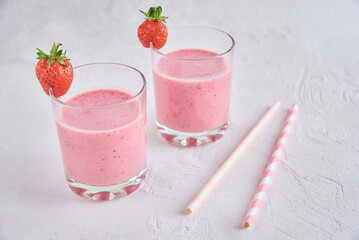 Strawberry milk shake in glass with straw and fresh berries on a white background