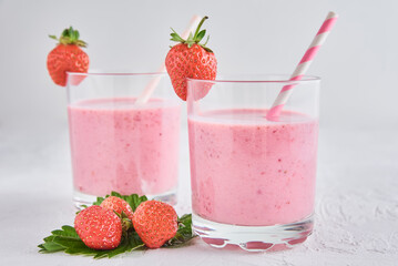 Strawberry milk shake in glass with straw and fresh berries on a white background