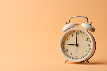 White vintage alarm clock on pastel orange paper background.