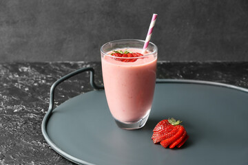 Glass of tasty strawberry smoothie on dark background