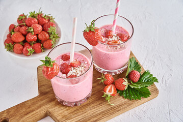 Strawberry milk shake in glass with straw and fresh berries on a white background