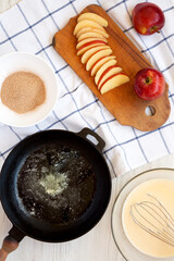 Cooking Apple Dutch Pannekoek Pancake on a white wooden surface, top view. Overhead, from above.