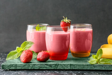 Glasses of tasty strawberry smoothie on dark background