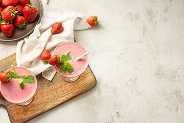 Glasses of tasty strawberry smoothie on grey background