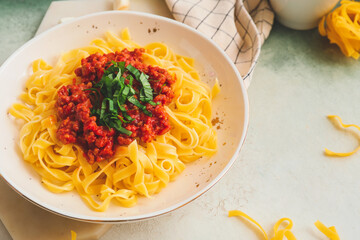 Plate with tasty pasta bolognese on light background
