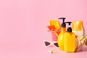 Sunscreen cream with beach sand toys on color background