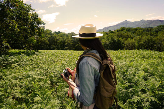 Woman with hat taking pictures in beautiful and natural landscape