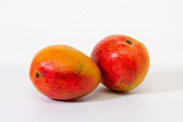 Two mangoes close-up on a light background.