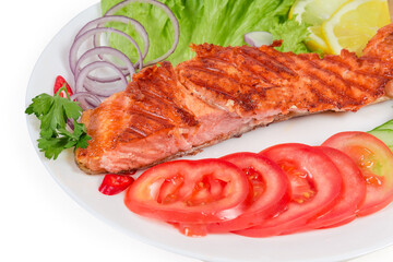 Piece of grilled trout fillet among the vegetables close-up
