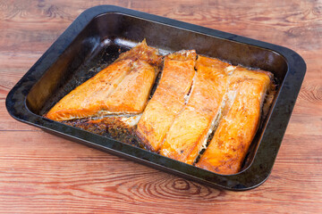 Baked trout fillet on metal oven tray on rustic table