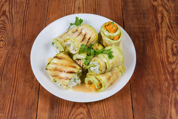 Zucchini rolls with different filling on dish on rustic table