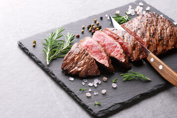 Beef steak and rosemary on a slate board background. Roast beef medium rare.