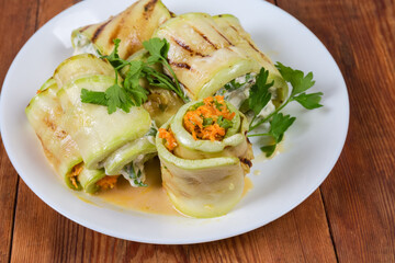 Zucchini rolls with different filling on dish close-up