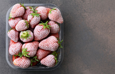 Frozen strawberries in a plastic container.