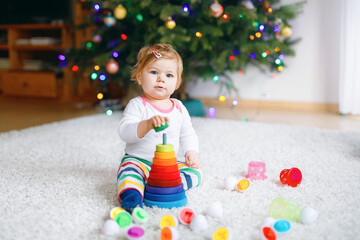 Adorable cute beautiful little baby girl playing with educational toys at home or nursery. Happy...