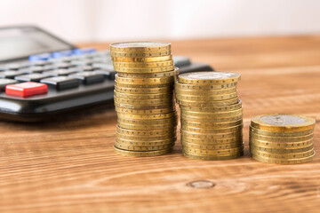 A stack of coins and a calculator on a wooden table. Concept of savings and financial accounting. Selective focus.