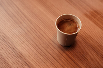 Top view shot of natural paper cup with hot coffee on the wooden table in cafe. Eco friendly disposable organic bamboo glass with americano, espresso, ristretto or other types of coffee. Copy space.