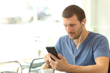 Man with headphones listens music on phone in a coffee shop