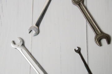 Several wrenches on a light wooden surface with copy space