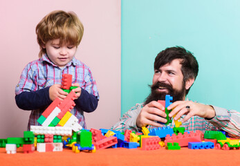 Father son game. Father and son create colorful constructions with bricks. Bearded father and boy play together. Dad and kid build of plastic blocks. Useful toy. Child care development and upbringing