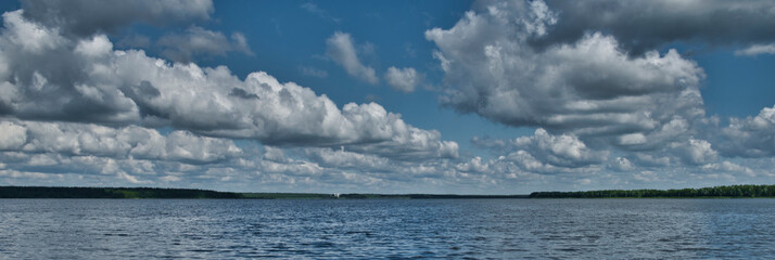 landscape panorama of a cloudy day on the lake with a small church on the other side