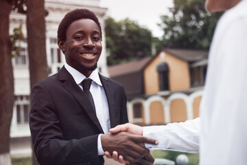 Selective focus of handsome businessman hand shaking. Cropped view of young adult african american recruiter have a business meeting with european male. Multiracial relationship concept.
