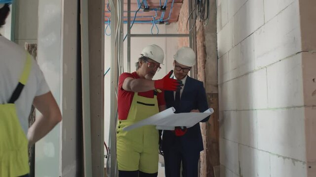 Foreman shows house design plans to businessman at construction site