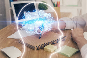 Multi exposure of writing hand on background with brain hologram. Concept of self learning.