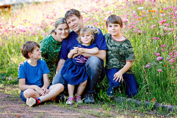 Summer portrait of parents with three children. Mother, father, two kids brothers boys and little...
