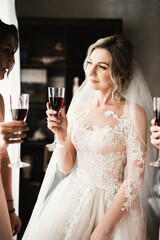 Photo bride with her friends drinking champagne from glasses