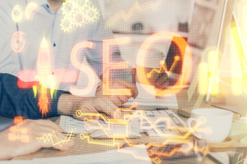 Multi exposure of seo icon with man working on computer on background. Concept of search engine optimization.