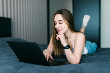 Fototapeta na wymiar Pretty woman using her laptop in bed at home