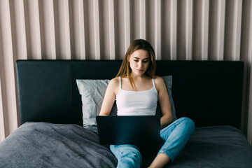 Pretty woman using her laptop in bed at home