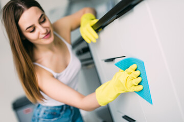 Young smiling woman cleans the kitchen at her home